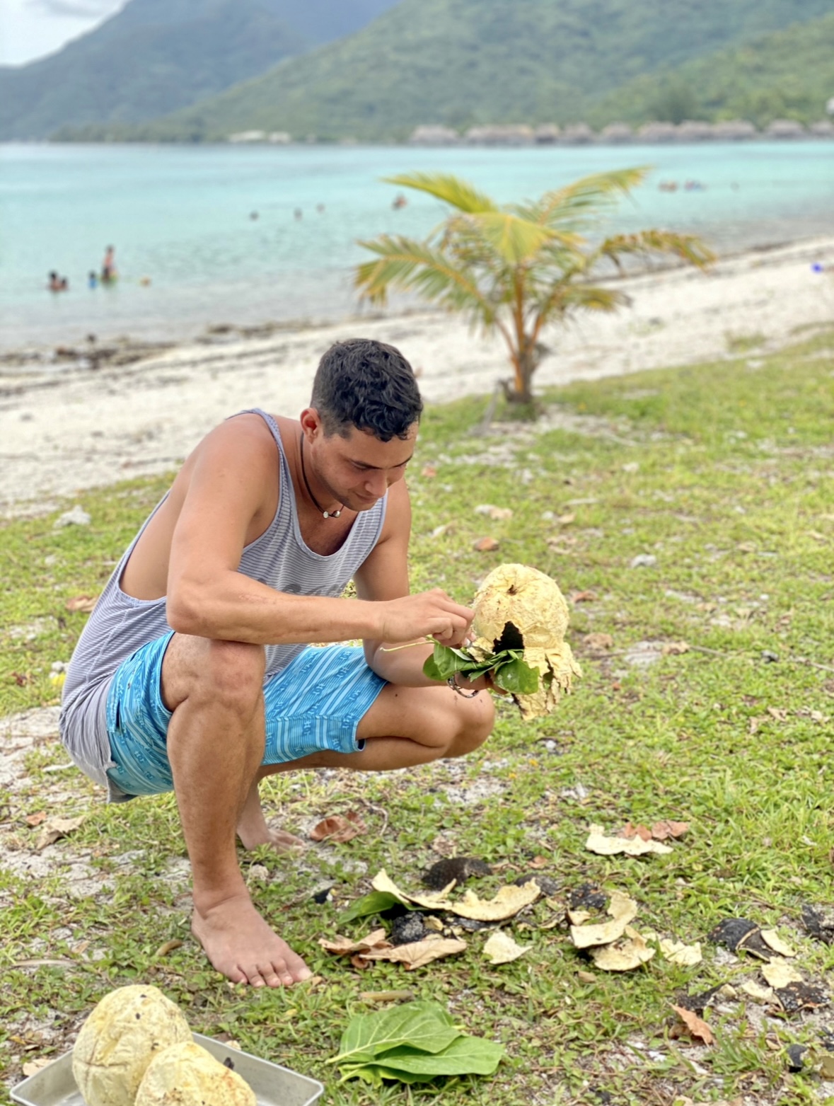 A very handsome man peeling the skin off of a freshly cooked Uru Moorea French Polynesia