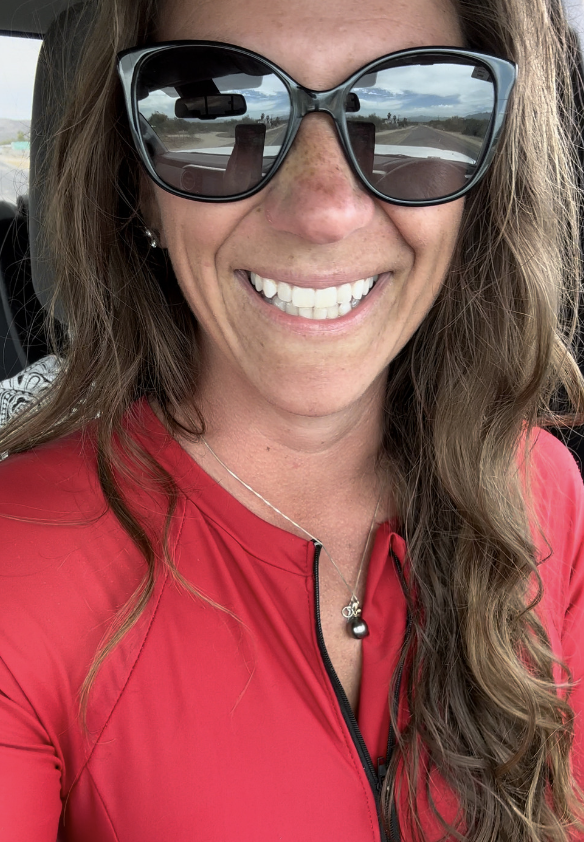 Hi From Ashley in a red rash guard, sunglasses and a big smile