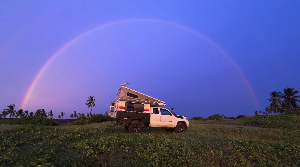 FAVORITE MEXICO CAMPING SPOTS VIBRANT BLUE SKY WITH A RAINBOW AND TOYOTA TACOMA PARKED RIGHT IN THE MIDDLE